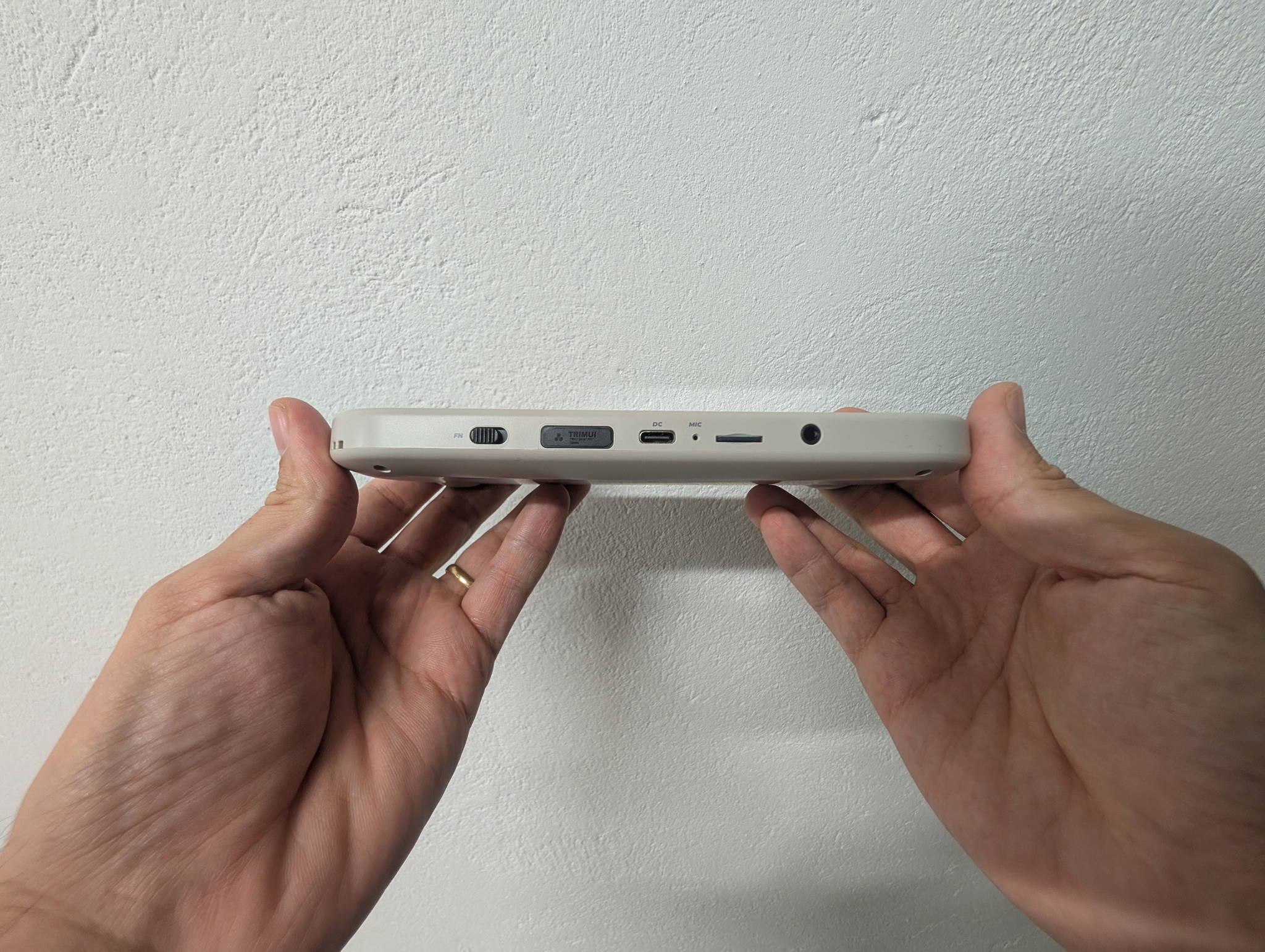 TrimUI Smart Pro shown from the front, screen off, showing the laminated glass panel
